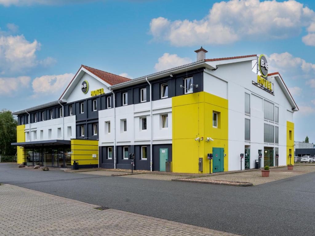 um edifício amarelo e branco ao lado de uma rua em B&B Hotel Hannover-Nord em Hanôver