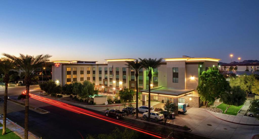 a city street at night with cars parked in front of a building at Hampton Inn Phoenix Airport North in Phoenix