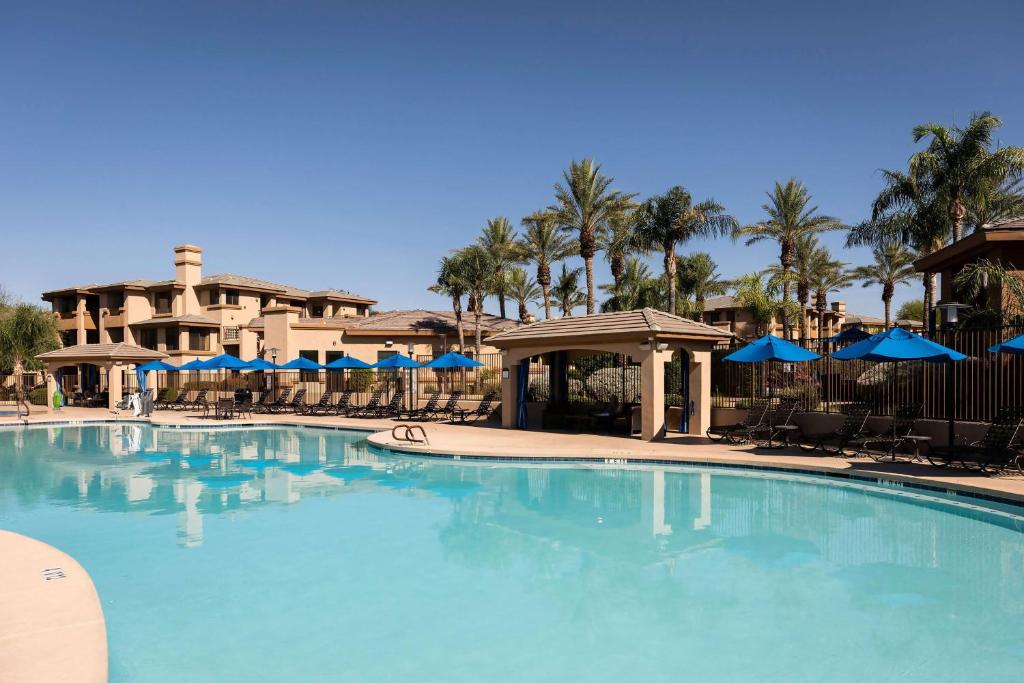 a large swimming pool with blue umbrellas in a resort at Hilton Vacation Club Scottsdale Links Resort in Scottsdale