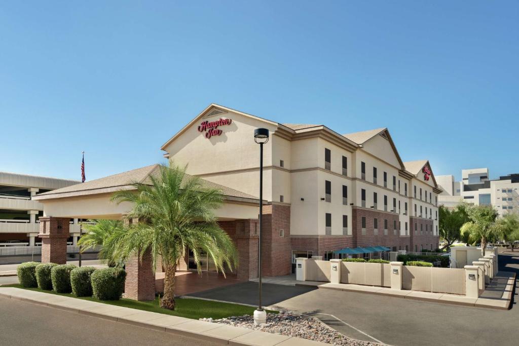 a building with a palm tree in front of a street at Hampton Inn Phoenix Midtown Downtown Area in Phoenix