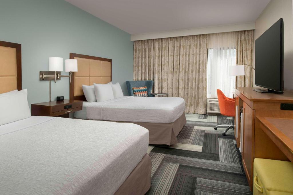 a hotel room with two beds and a flat screen tv at Hampton Inn Pittsburgh-Monroeville in Monroeville