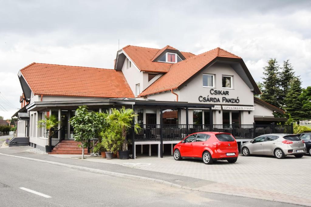 a building with cars parked in front of it at Csikar Csárda és Panzió in Kőszeg