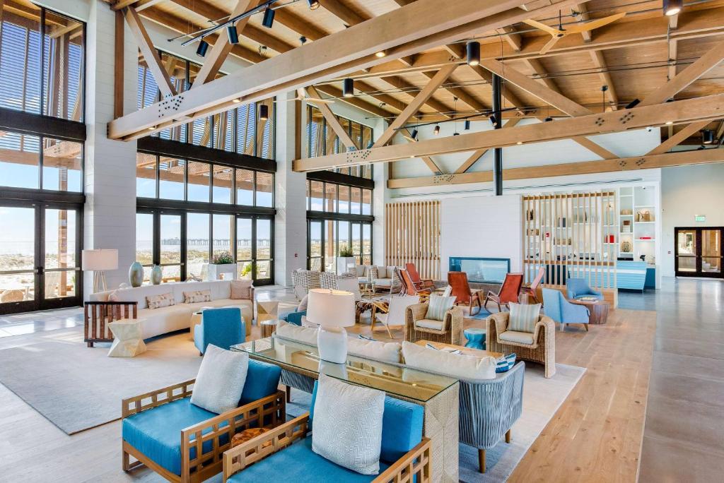 a living room with a lot of furniture and windows at The Lodge at Gulf State Park, A Hilton Hotel in Gulf Shores