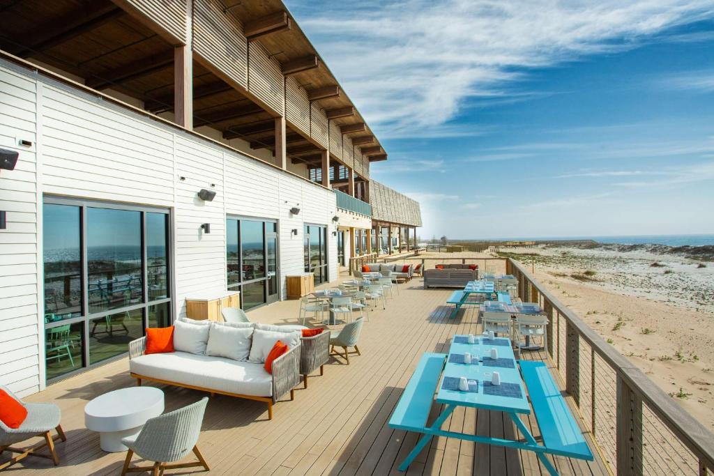 a deck with tables and couches on the beach at The Lodge at Gulf State Park, A Hilton Hotel in Gulf Shores