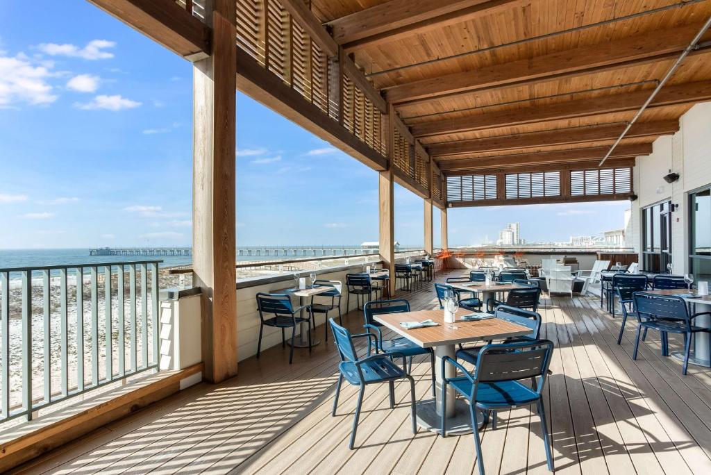 a patio with tables and chairs and the ocean at The Lodge at Gulf State Park, A Hilton Hotel in Gulf Shores