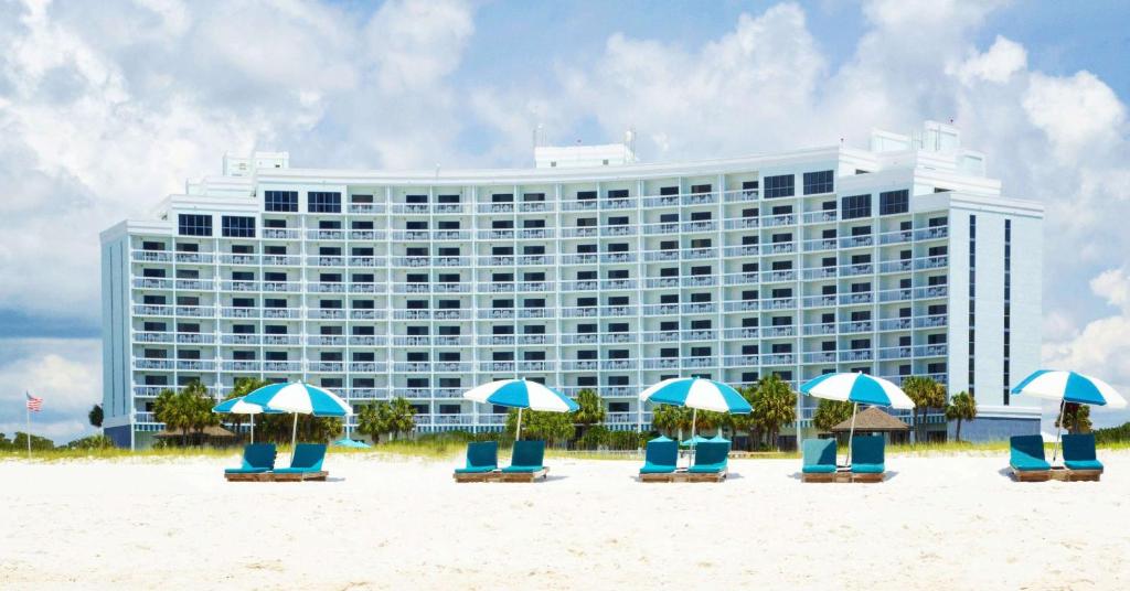 奧蘭治海灘的住宿－The Island House Hotel a Doubletree by Hilton，海滩上的酒店,配有椅子和遮阳伞