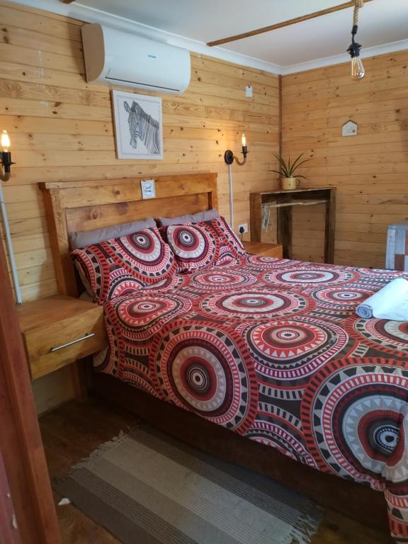 Schlafzimmer mit einem Bett mit einer roten Bettdecke in der Unterkunft The CabinGuesthouse in Gaborone
