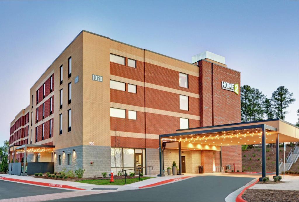 een bakstenen gebouw met een benzinestation ervoor bij Home2 Suites By Hilton Raleigh Durham Airport RTP in Durham