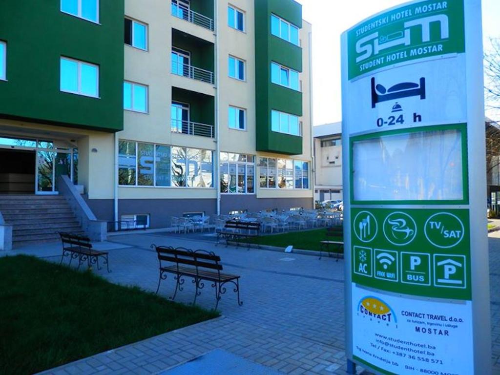 a sign in front of a building with benches at Student Hotel Mostar in Mostar