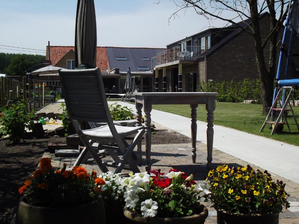 krzesło i stół w ogrodzie z kwiatami w obiekcie B&B Altijd Genieten w mieście Damme