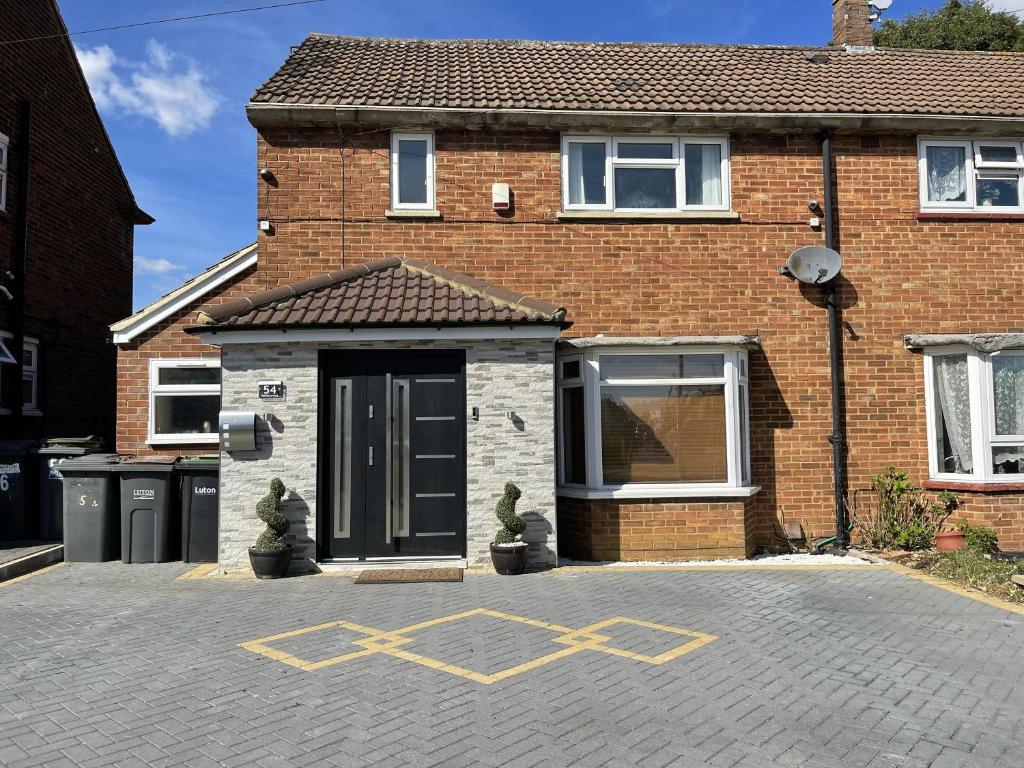 a brick house with a yellow cross on the driveway at New Luxury Modern House near Airport Free Parking in Luton