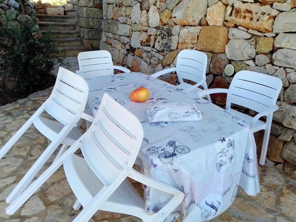 uma mesa com cadeiras brancas e uma laranja em Domus Veretum em Morciano di Leuca