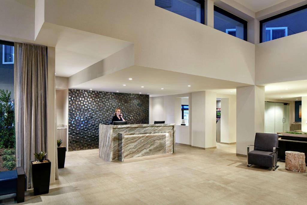 a woman standing at a counter in a lobby at Hilton Garden Inn San Diego Mission Valley/Stadium in San Diego