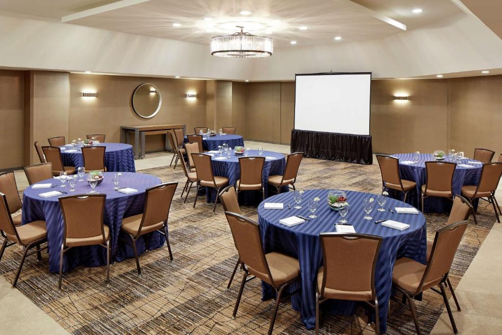 a conference room with tables and chairs and a screen at Hilton Garden Inn San Diego Mission Valley/Stadium in San Diego
