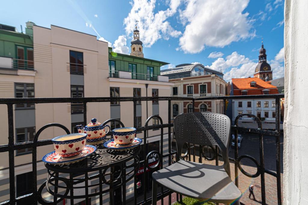 d'un balcon avec une table, des chaises et des tasses. dans l'établissement Stylish Old Town apartment, à Riga