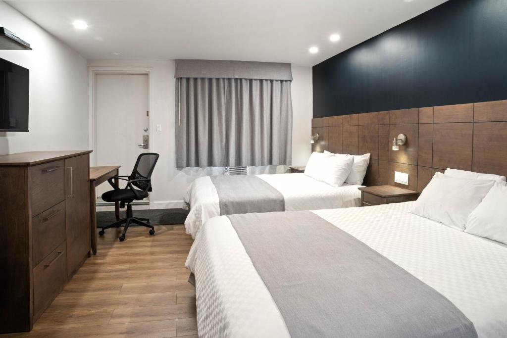 Habitación de hotel con 2 camas y escritorio en Hôtel Marineau Centre, en La Tuque