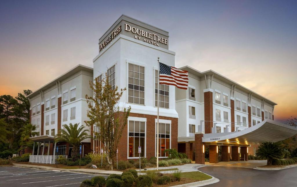 Um edifício com uma bandeira americana à frente. em DoubleTree by Hilton Hotel Savannah Airport em Savannah