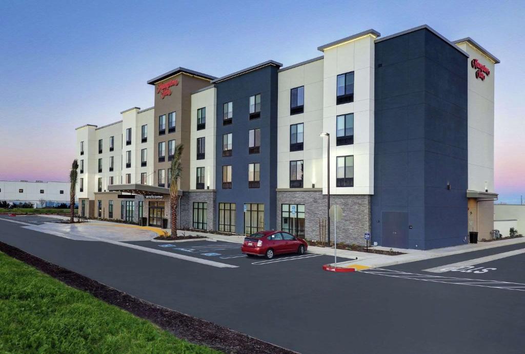 PattersonHampton Inn Patterson, Ca的一辆红色汽车停在一栋建筑物前