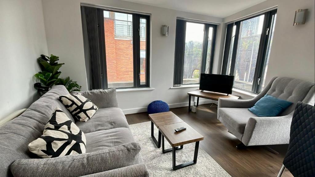 uma sala de estar com um sofá e duas cadeiras em 2 Bed Flat Near Deansgate em Manchester