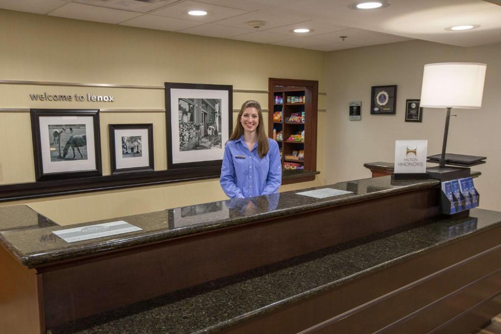 a woman standing at a counter in a waiting room at Hampton Inn & Suites Berkshires-Lenox in Lenox