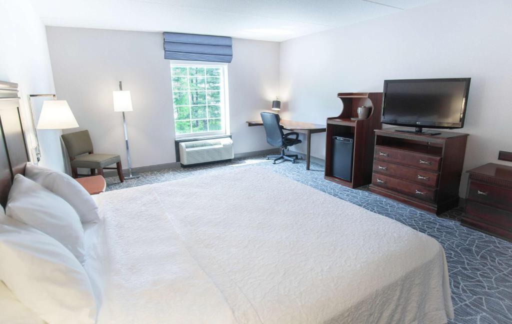 a hotel room with a bed and a flat screen tv at Hampton Inn & Suites Berkshires-Lenox in Lenox