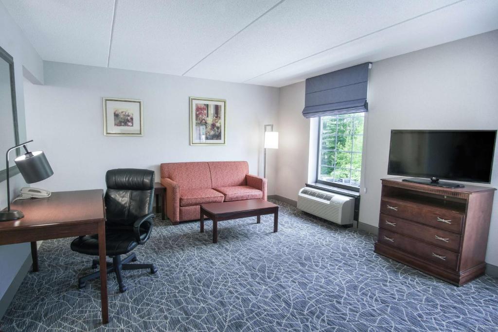 a hotel room with a desk and a television and a chair at Hampton Inn & Suites Berkshires-Lenox in Lenox
