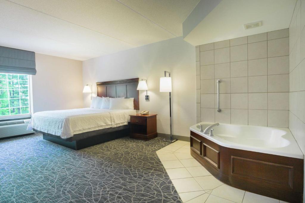 a hotel room with a bed and a bath tub at Hampton Inn & Suites Berkshires-Lenox in Lenox