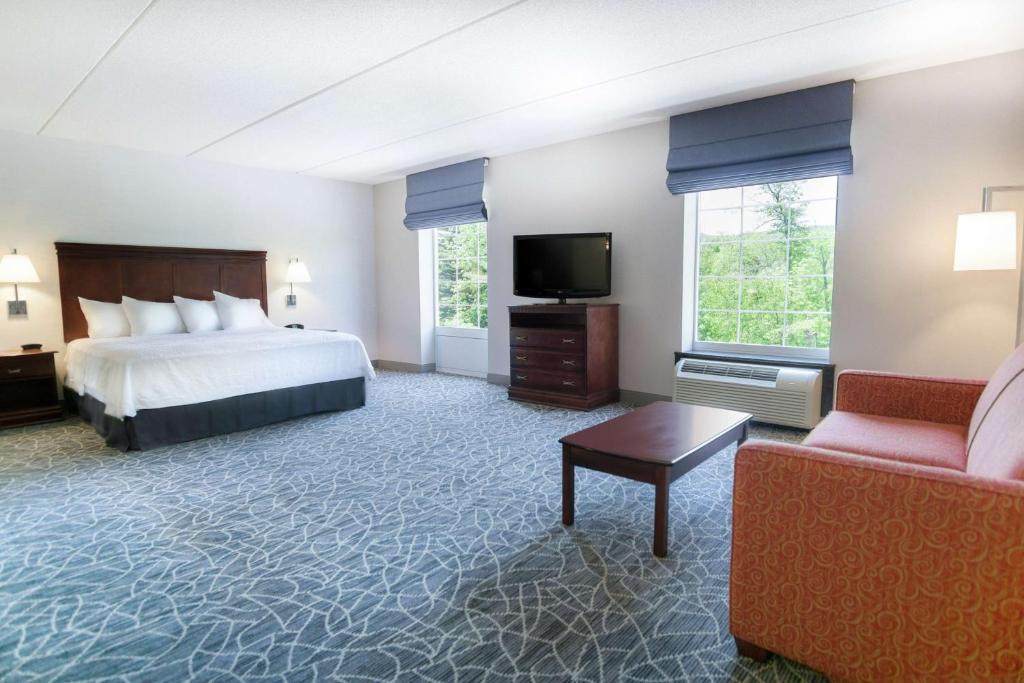 a hotel room with a bed and a tv and a couch at Hampton Inn & Suites Berkshires-Lenox in Lenox