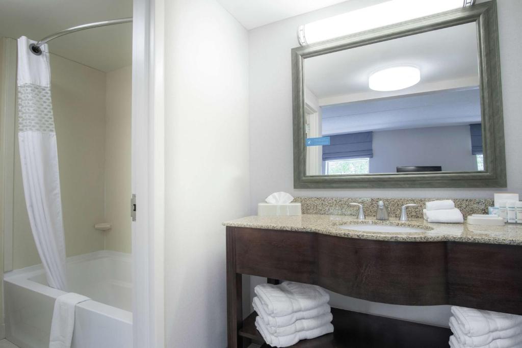 a bathroom with a sink and a tub and a mirror at Hampton Inn & Suites Berkshires-Lenox in Lenox