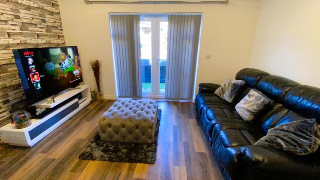 a living room with a leather couch and a flat screen tv at Bridgefield House in Ashford