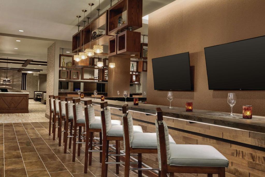 a bar with a row of chairs in a room at Embassy Suites By Hilton South Jordan Salt Lake City in South Jordan
