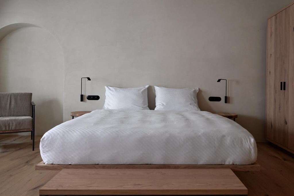 Brixen的住宿－fink Restaurant & Suites，一间卧室配有一张带两盏灯的大型白色床。