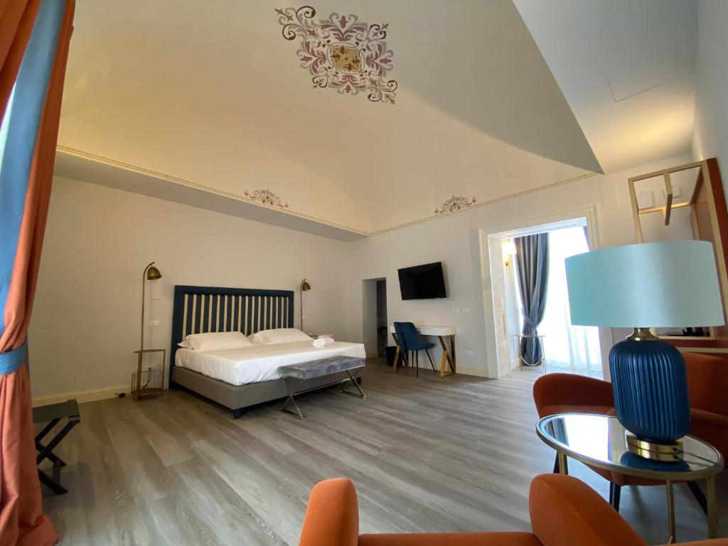 シラクーサにあるLanterne Magiche Ortigia Suitesのベッドルーム1室(ベッド1台付)、リビングルームが備わります。