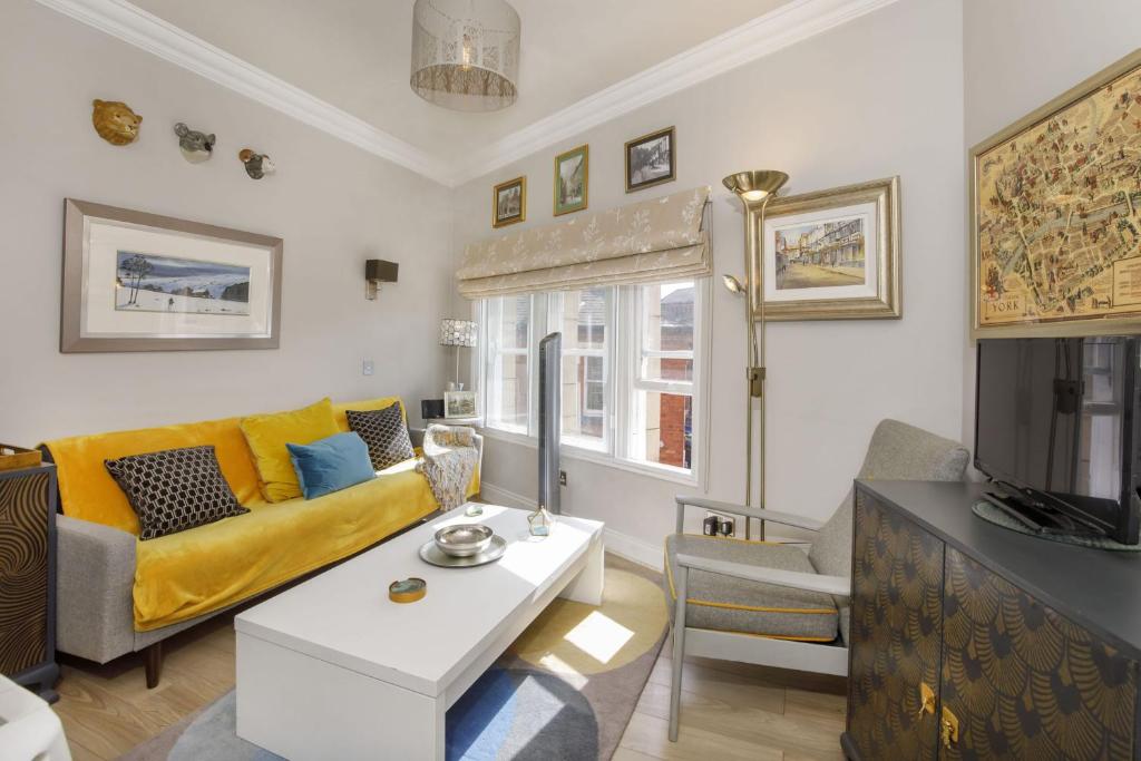 a living room with a yellow couch and a tv at Copper Gate Chambers in York