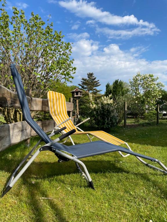 a chair sitting in the grass next to a fence at TinyHouse Meereszauber- ruhige Lage, eigener Garten, Grill in Wolgast