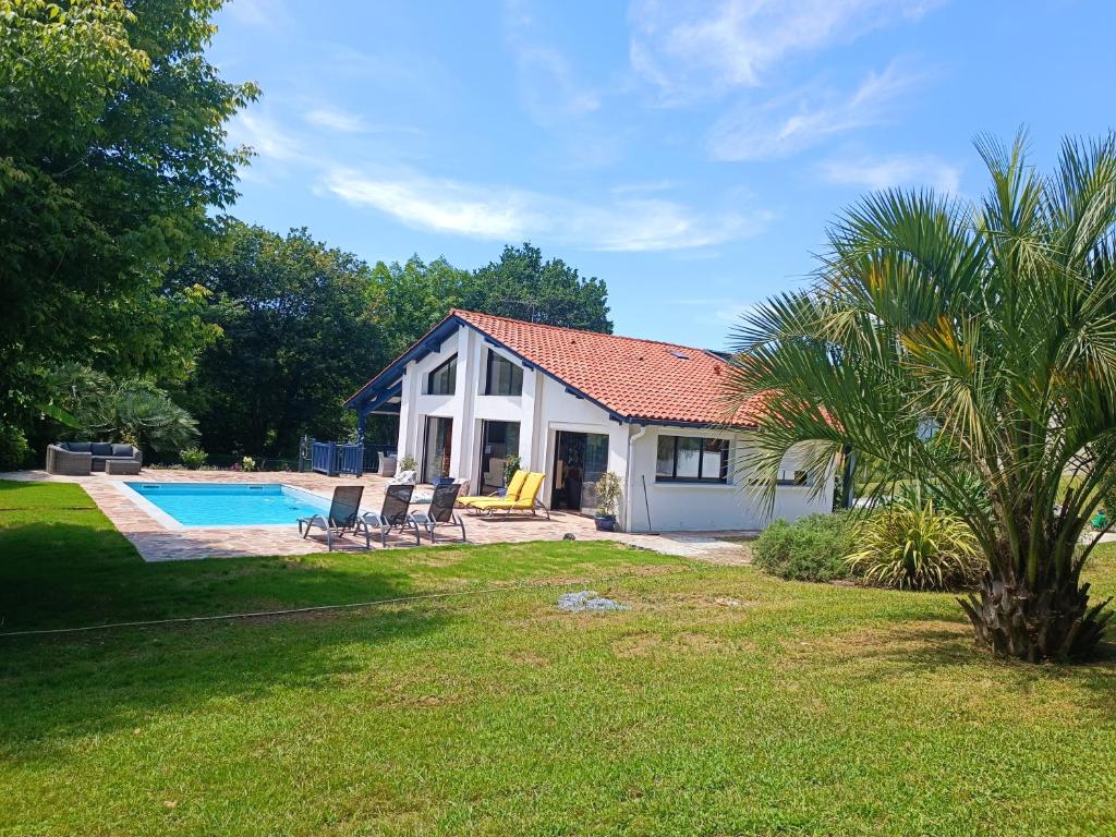 una casa con piscina, sillas y una palmera en Près golfs et plages piscine chauffée, en Bidart