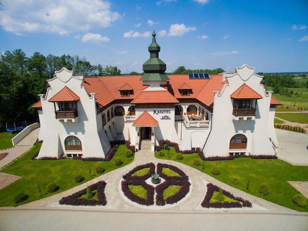 a large building with a tower and a garden at Hotel Kasztel in Rzezawa