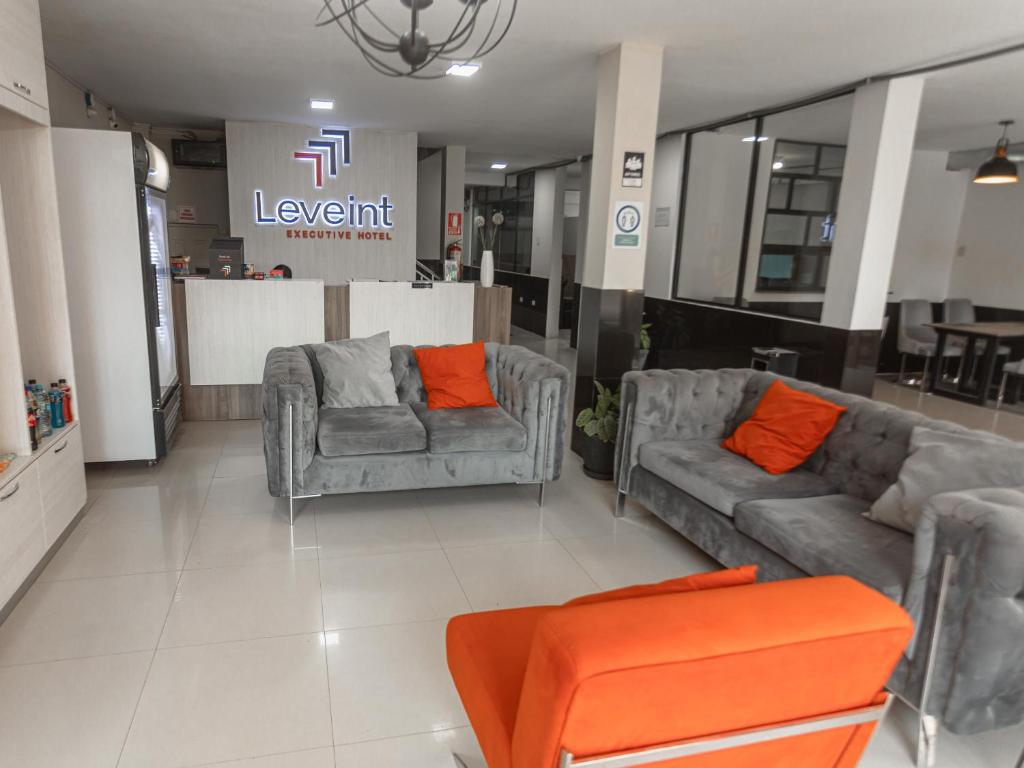 una sala de estar con 2 sofás y una silla naranja en Leveint Executive Hotel, en Pucallpa