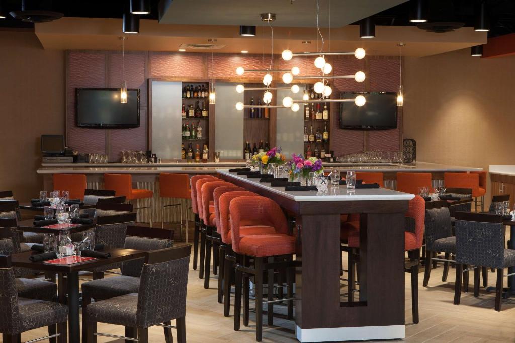 a restaurant with a long bar with orange chairs at DoubleTree by Hilton Johnson City in Johnson City