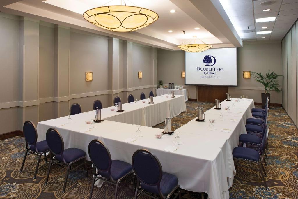 a conference room with tables and chairs and a screen at DoubleTree by Hilton Johnson City in Johnson City