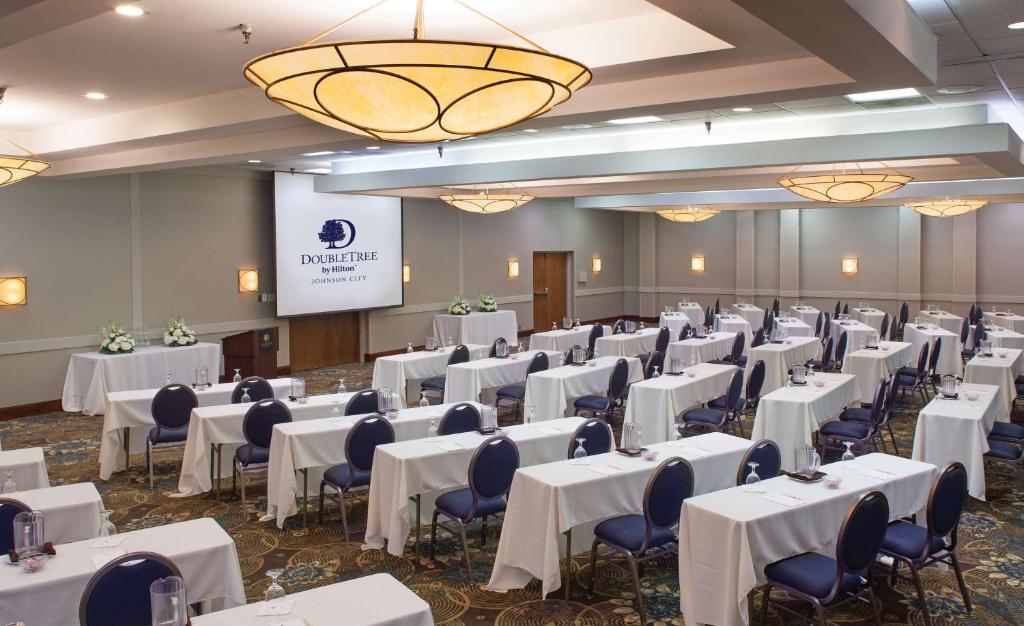 a conference room with white tables and chairs and a screen at DoubleTree by Hilton Johnson City in Johnson City