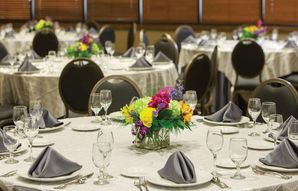 a group of tables with plates and glasses and a vase of flowers at DoubleTree by Hilton Johnson City in Johnson City