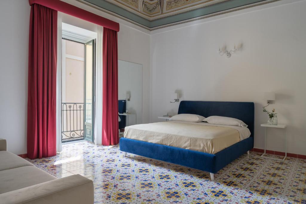 1 dormitorio con cama con cortinas rojas y sofá en Residenza Amalphia, en Amalfi