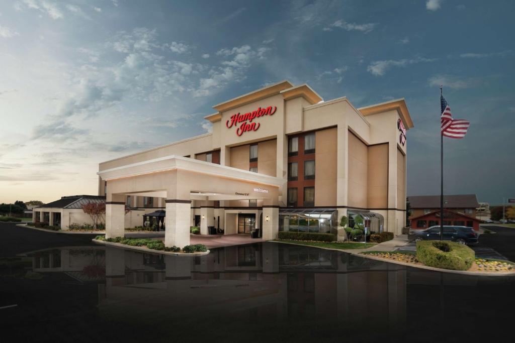 un edificio de hotel con una bandera americana delante de él en Hampton Inn Tulsa/Broken Arrow en Broken Arrow