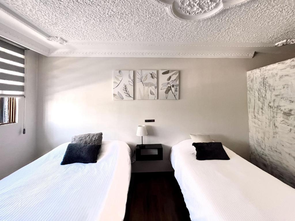 two beds in a room with white walls at Casa La Purísima in Guadalajara