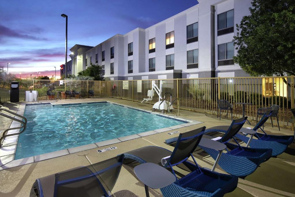 a swimming pool with chairs and a building at Hampton Inn & Suites Tucson East in Tucson