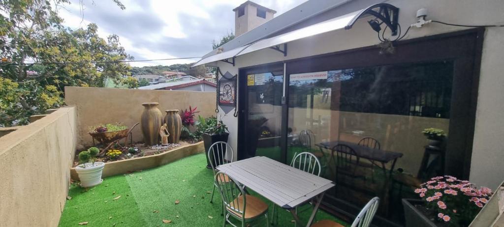 a small patio with a white table and chairs at Moeg Geploeg Lodge in Port Shepstone