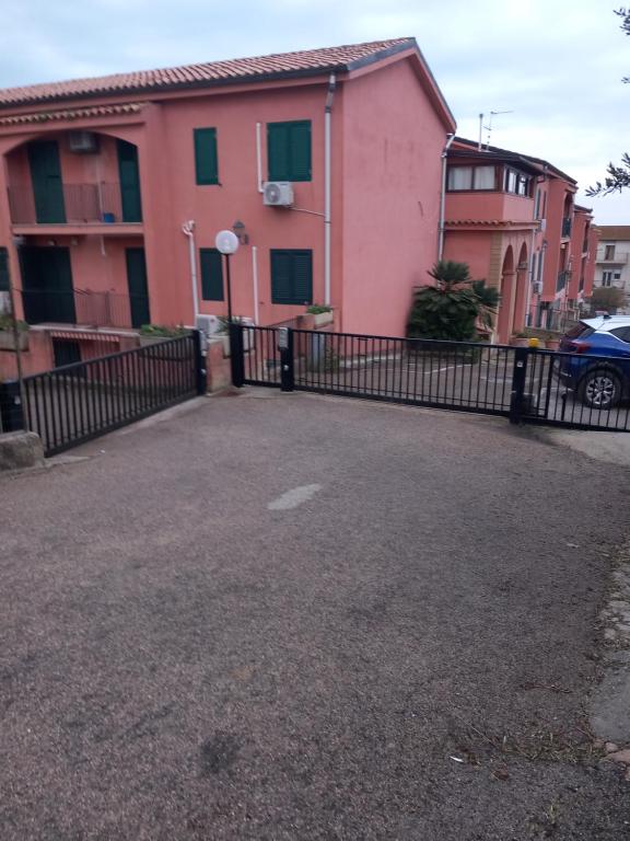uma casa cor-de-rosa com uma cerca preta à frente. em Casa Residence Canalotto em Realmonte