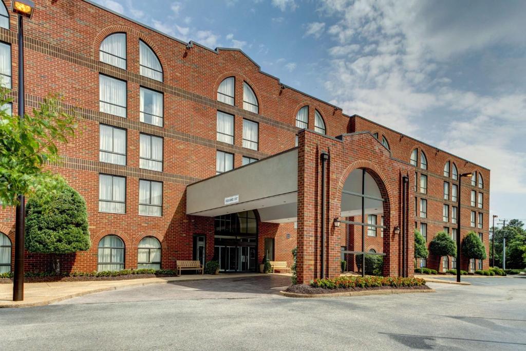 a large red brick building with a parking lot at Embassy Suites Williamsburg in Williamsburg