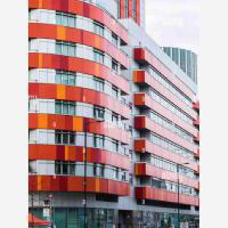 a tall red and white building with many windows at Tee SweetLux Apartment In Canning Town in London
